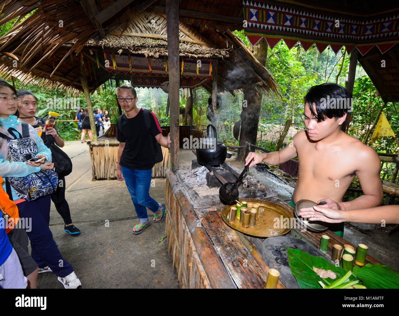 Chinese tourists watching a Malaysian man serving rice alcohol, Mari Mari Cultural Village, Kota Kinabalu, Sabah, Borneo, Malaysia Stock Photo
