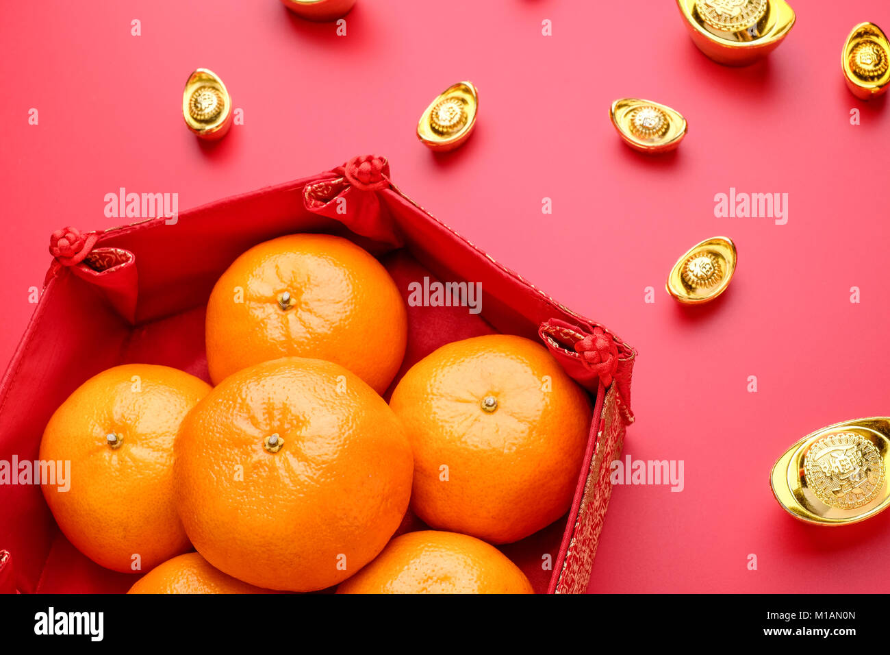 Group of orange tangerine in Chinese pattern tray with gold ingots on