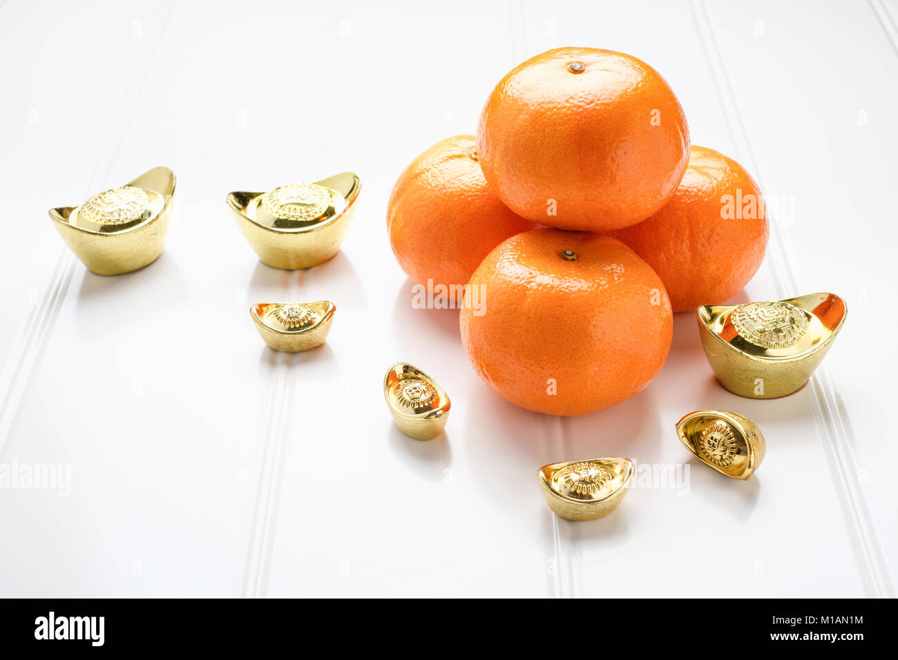 Chinese New year,gold ingots and tangerine oranges on white wood table top,Chinese Language ingot mean wealthy Stock Photo