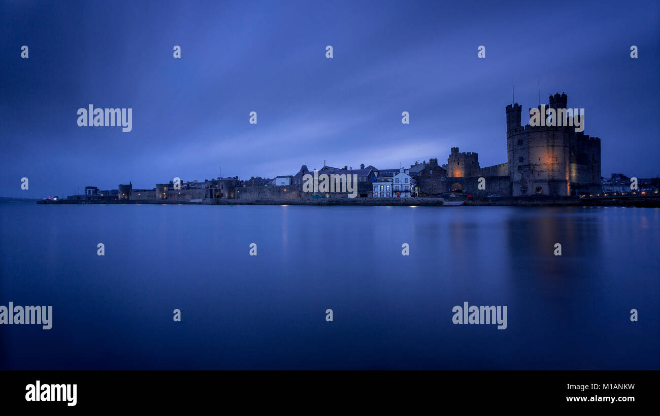 Caernarfon castle and walls at twilight on the North Wales coast Stock Photo