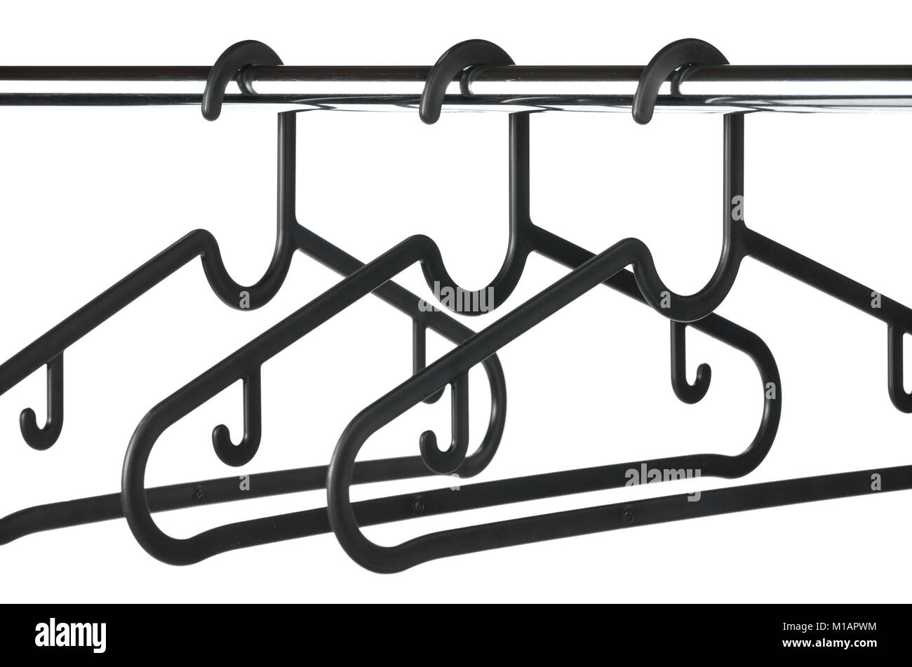 Three empty black coat / clothes hangers on a clothes rail with a white