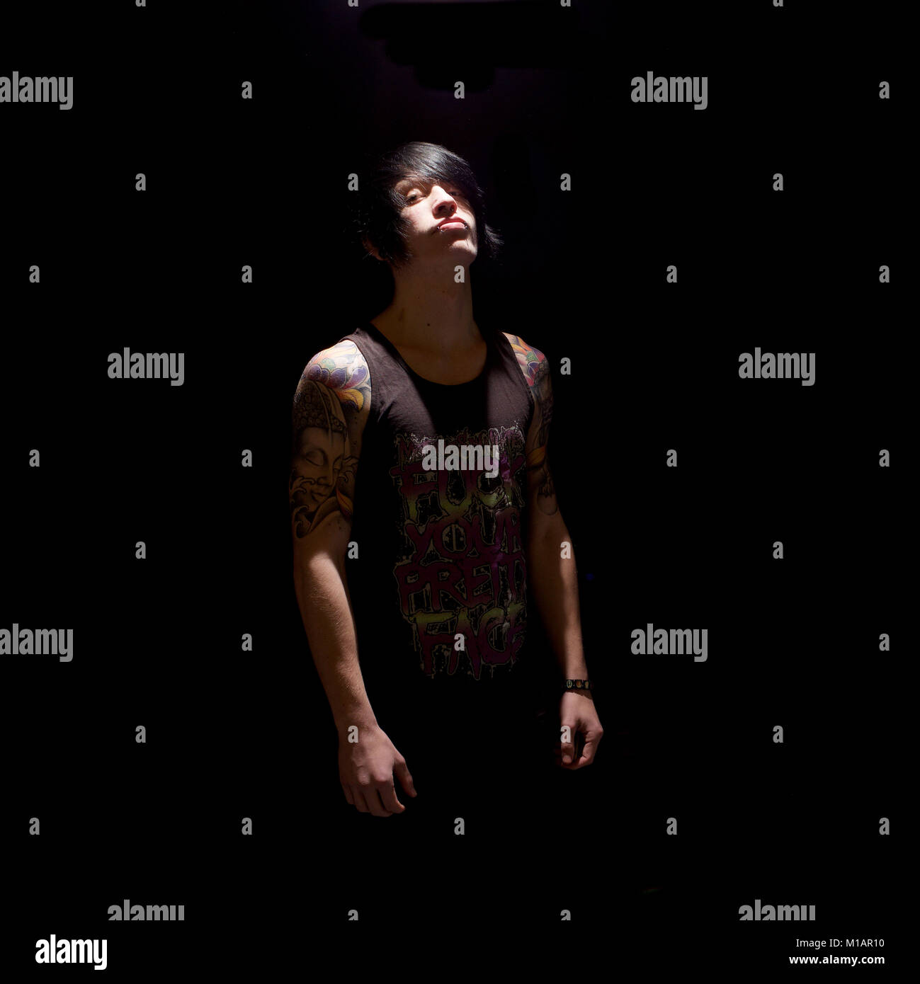 Young man with tattoos in a studio - black background Stock Photo