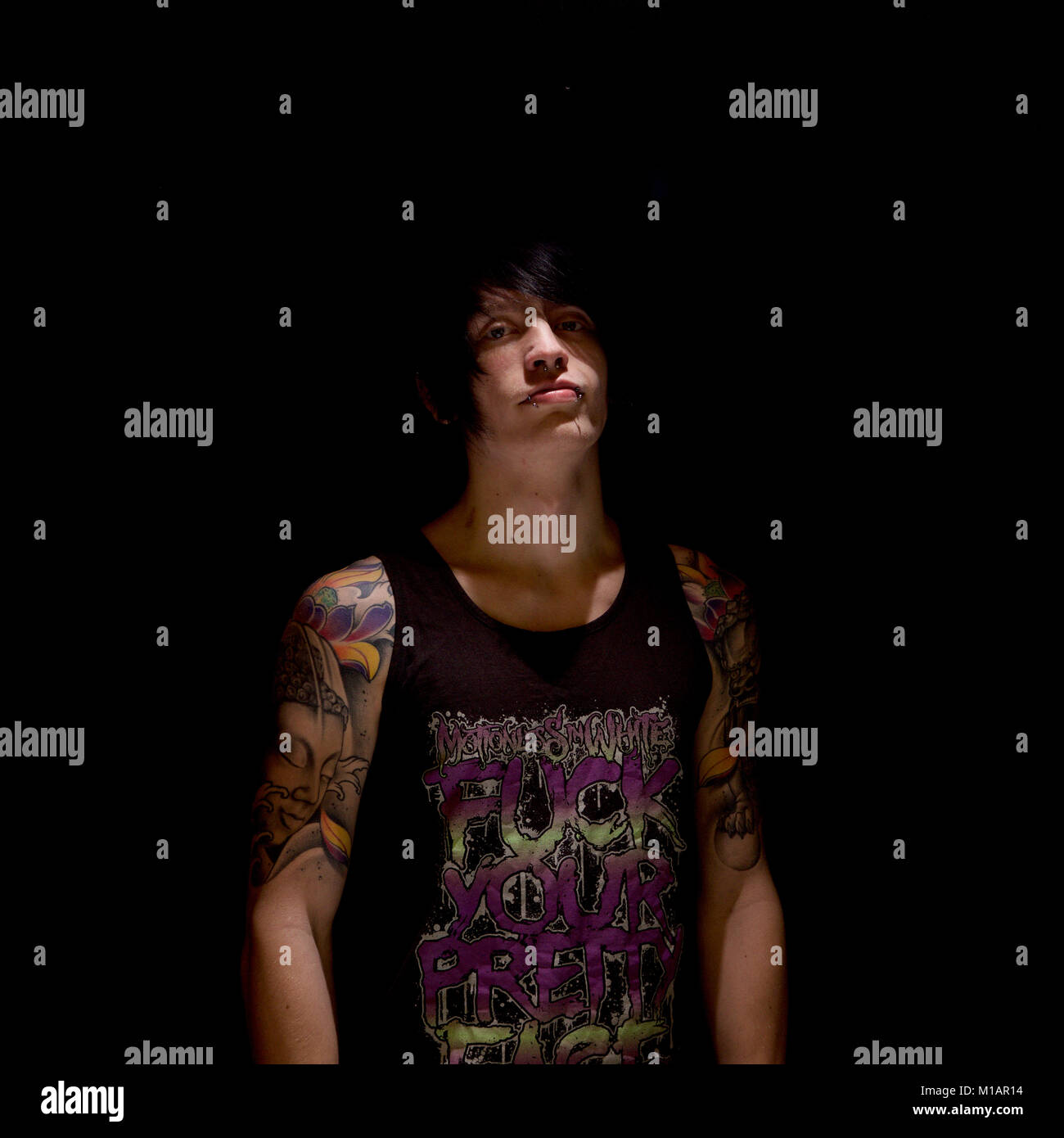 Young man with tattoos in a studio - black background Stock Photo