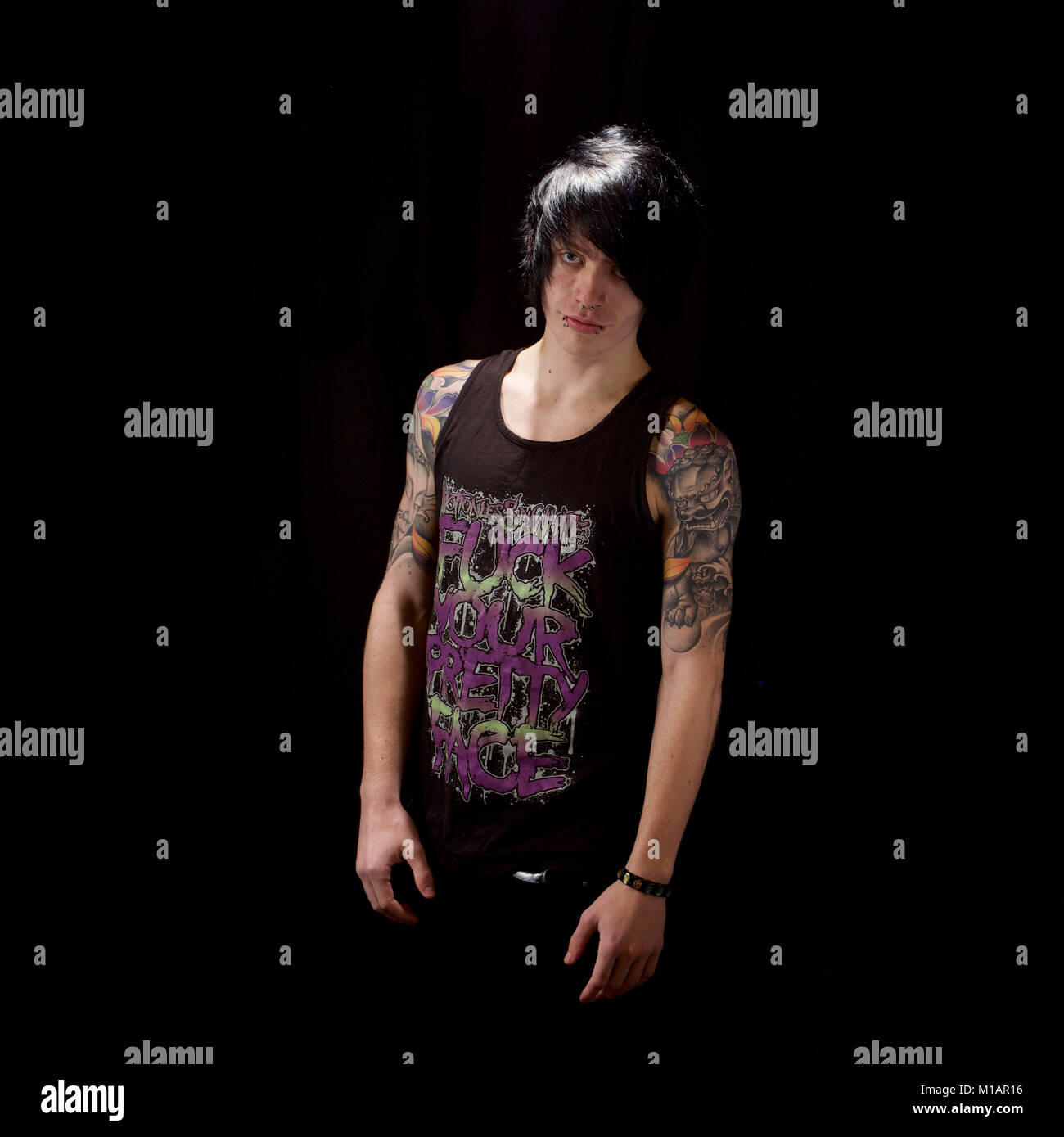 Young man with tattoos in a studio - black background Stock Photo