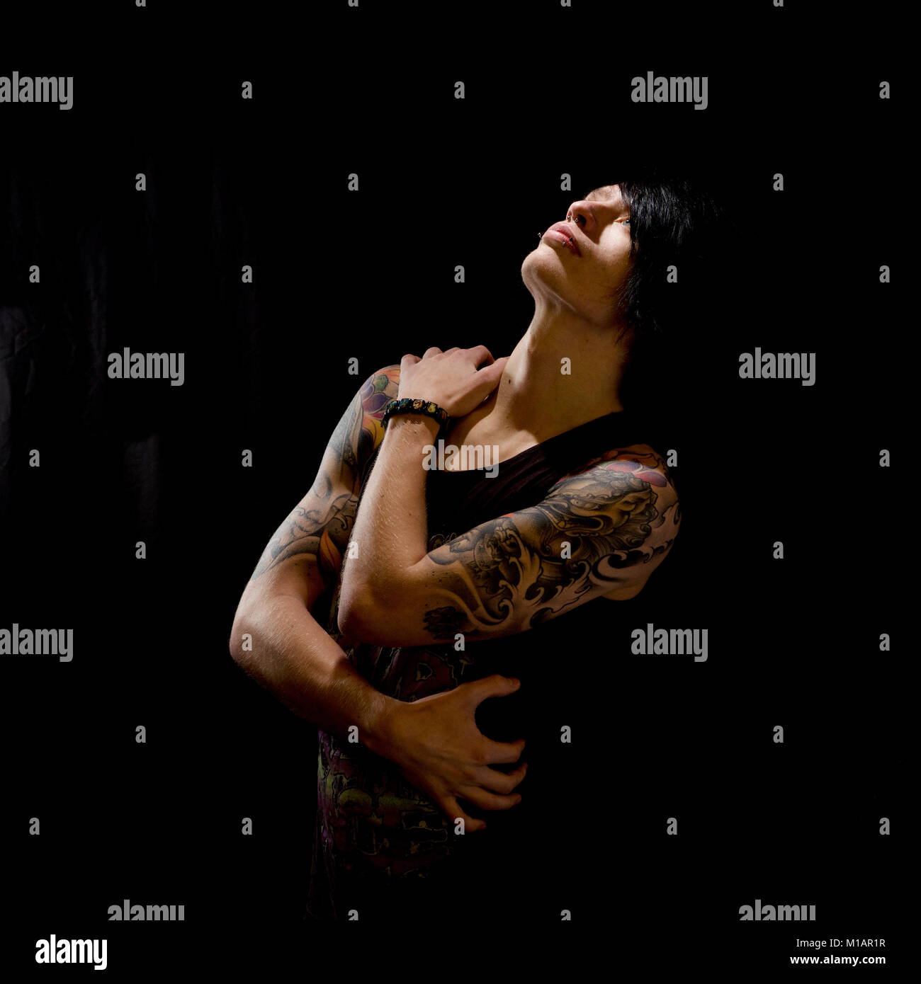 Young man with tattoos in a studio - black background Stock Photo
