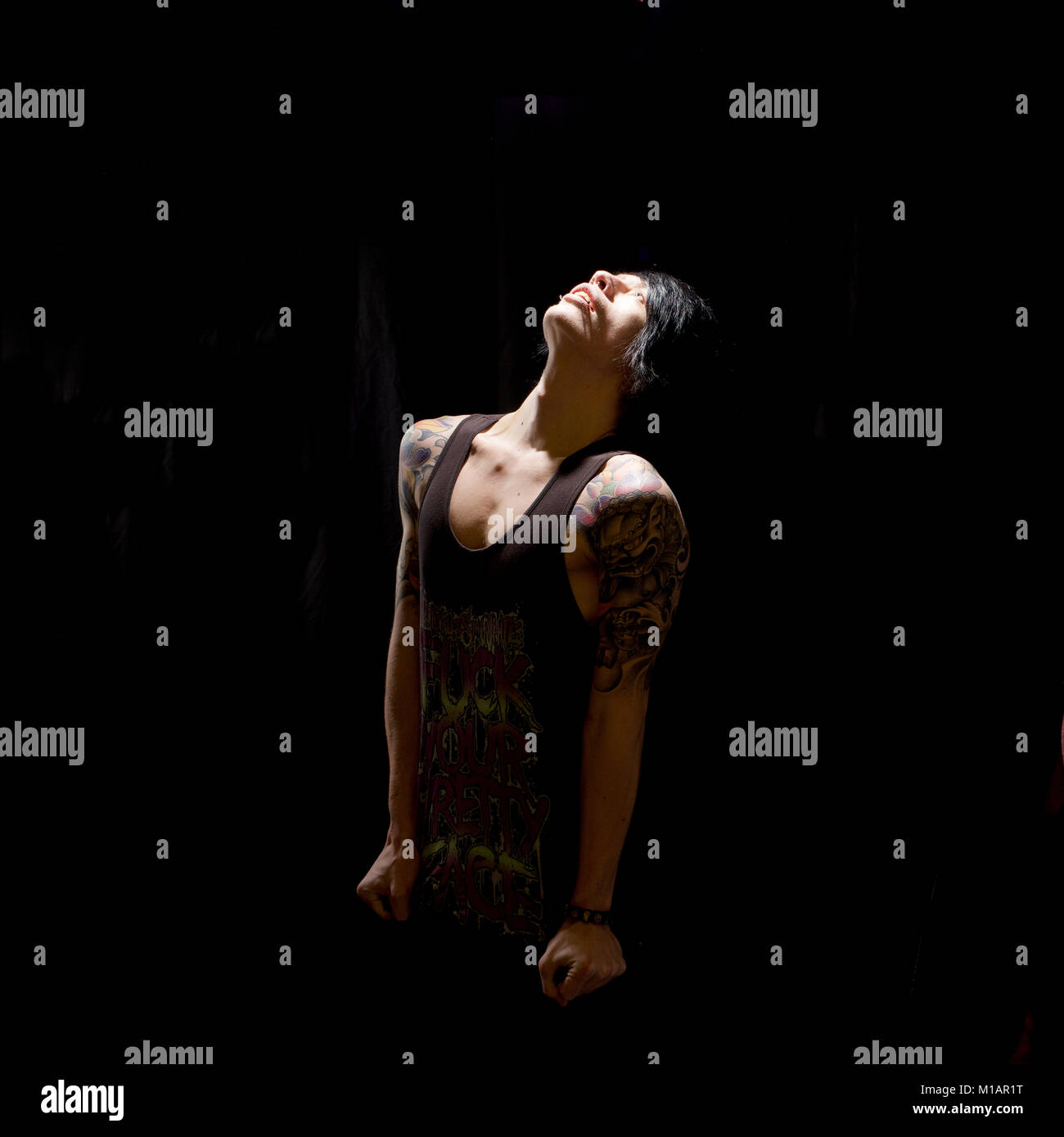 Young man with tattoos in a studio - black background Stock Photo