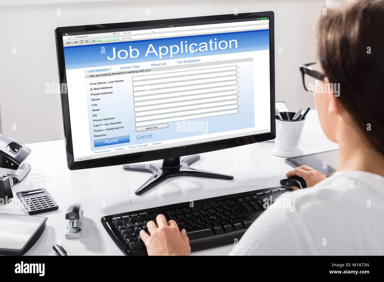 Rear View Of A Woman Filling Job Application On Desk Stock Photo