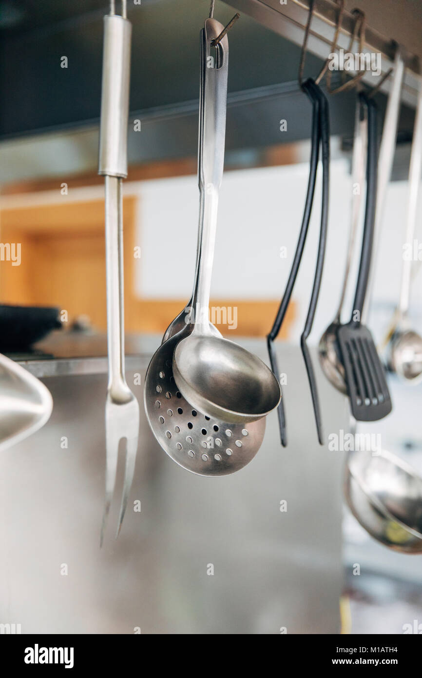 https://c8.alamy.com/comp/M1ATH4/close-up-shot-of-metallic-utensils-hanging-at-kitchen-of-restaurant-M1ATH4.jpg