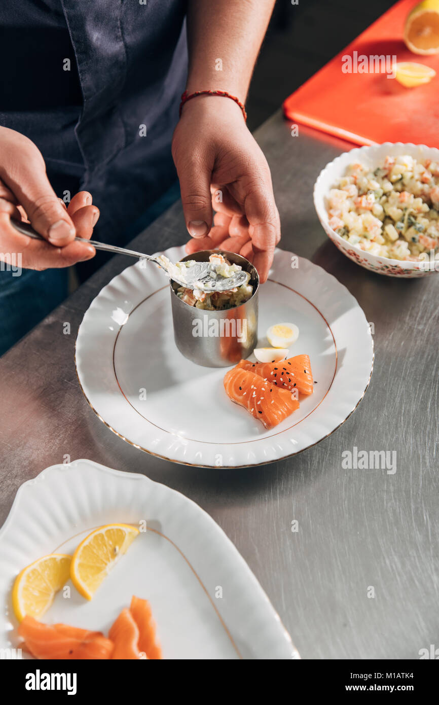 cropped shot of chef preparing salad with metal forming tube at restaurant Stock Photo