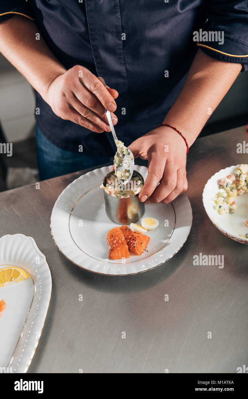 cropped shot of chef preparing salad with metal forming tube and spoon at restaurant Stock Photo
