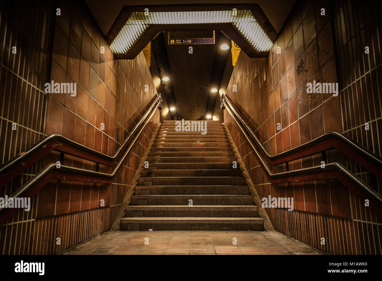 Stairs leading up from underground tunnel at a train station. Brown, dark color tones, scary, moody, atmospheric look. Stock Photo
