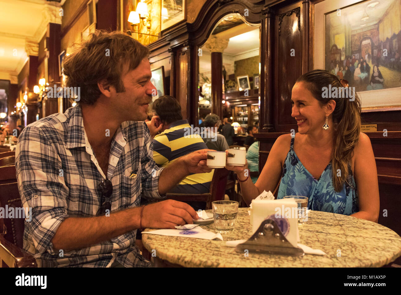 A young couple of tourists drinks a coffee inside the famous 'Café Tortoni'. Buenos Aires, Argentina. Stock Photo