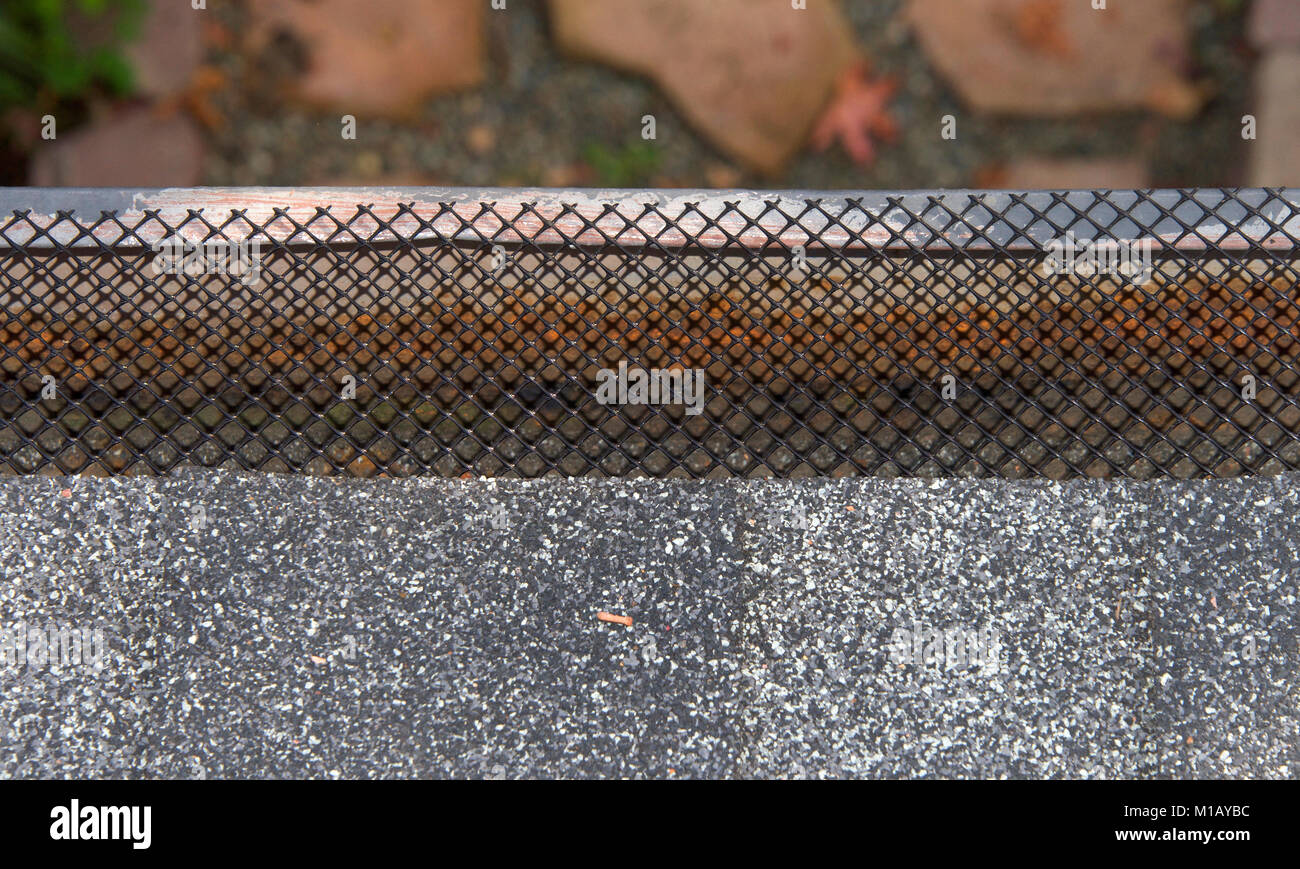 Close up on section of rain gutter on residential home, free of leaves and debri, covered with mesh. mesh helps to keep leaves and debri out of rain g Stock Photo