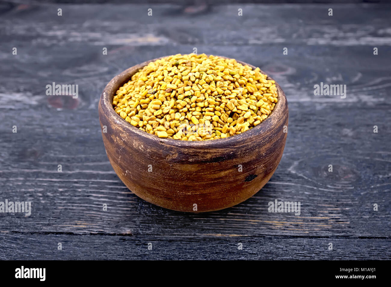 Fenugreek seeds in a clay bowl on the background of a black wooden board Stock Photo