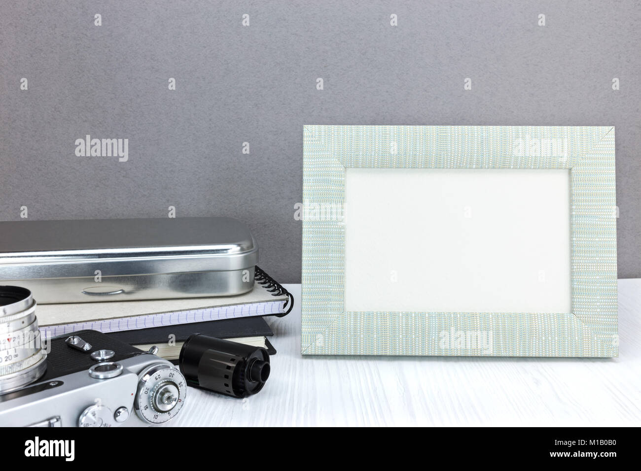 retro camera, notebook, negative film roll and empty photo frame on grey wall background Stock Photo