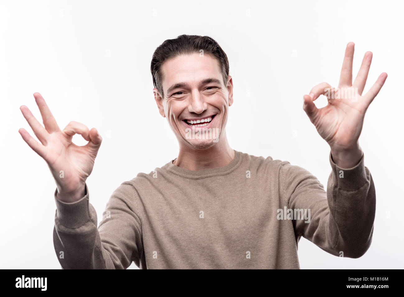 Cheerful man showing two OK signs and smiling Stock Photo - Alamy