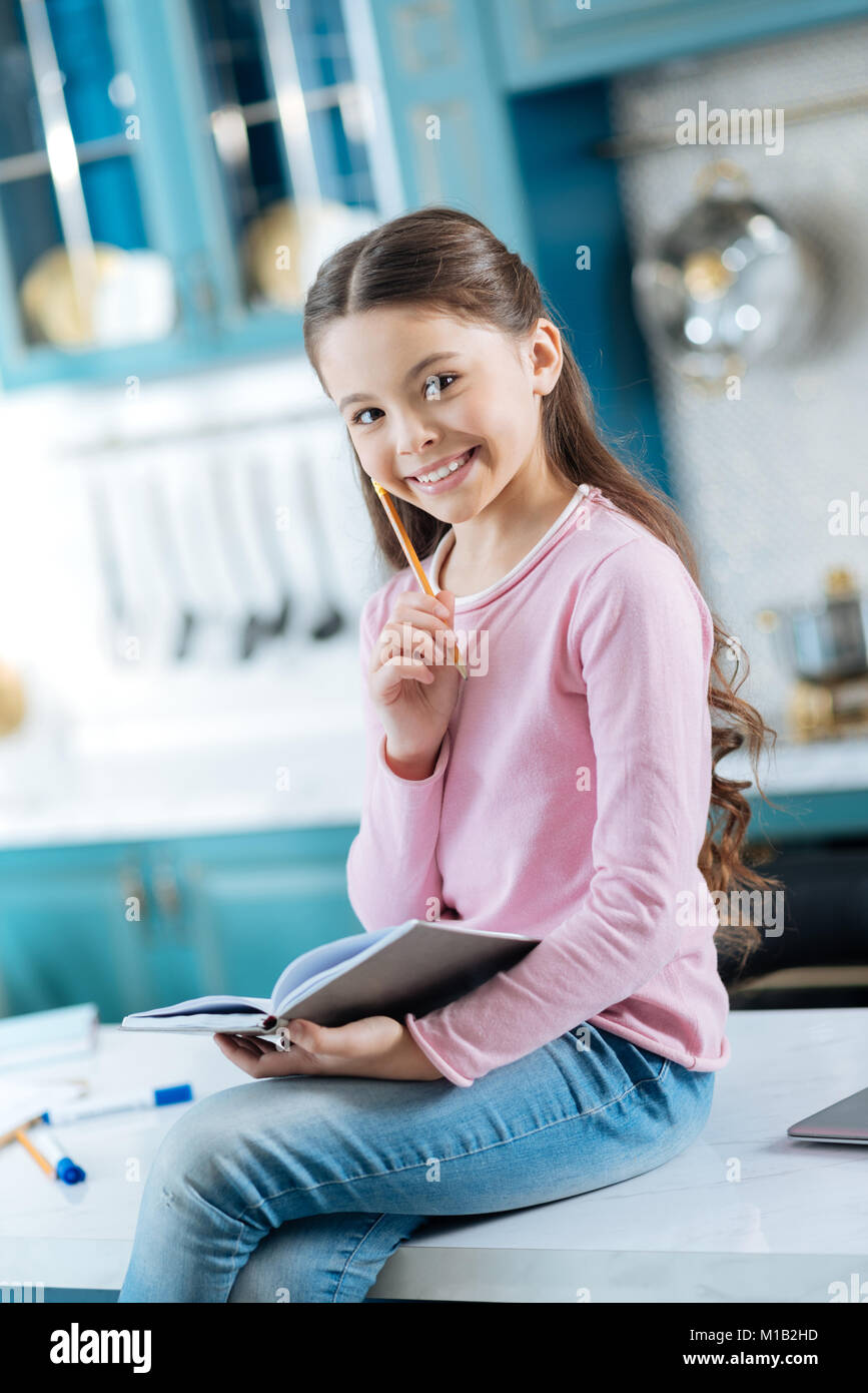Smiling little girl sitting on the table Stock Photo - Alamy