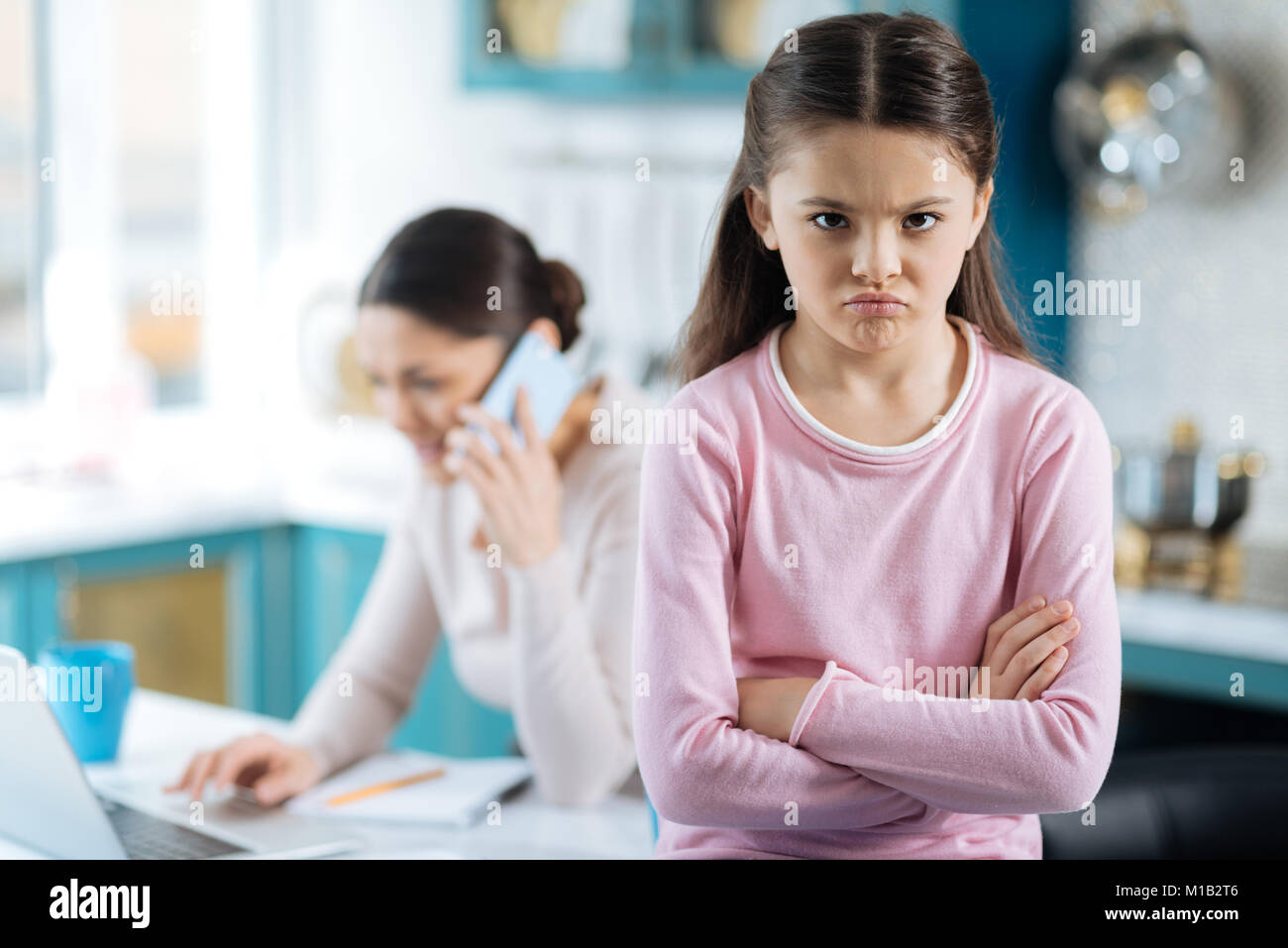 Resentful little girl and her mom working Stock Photo