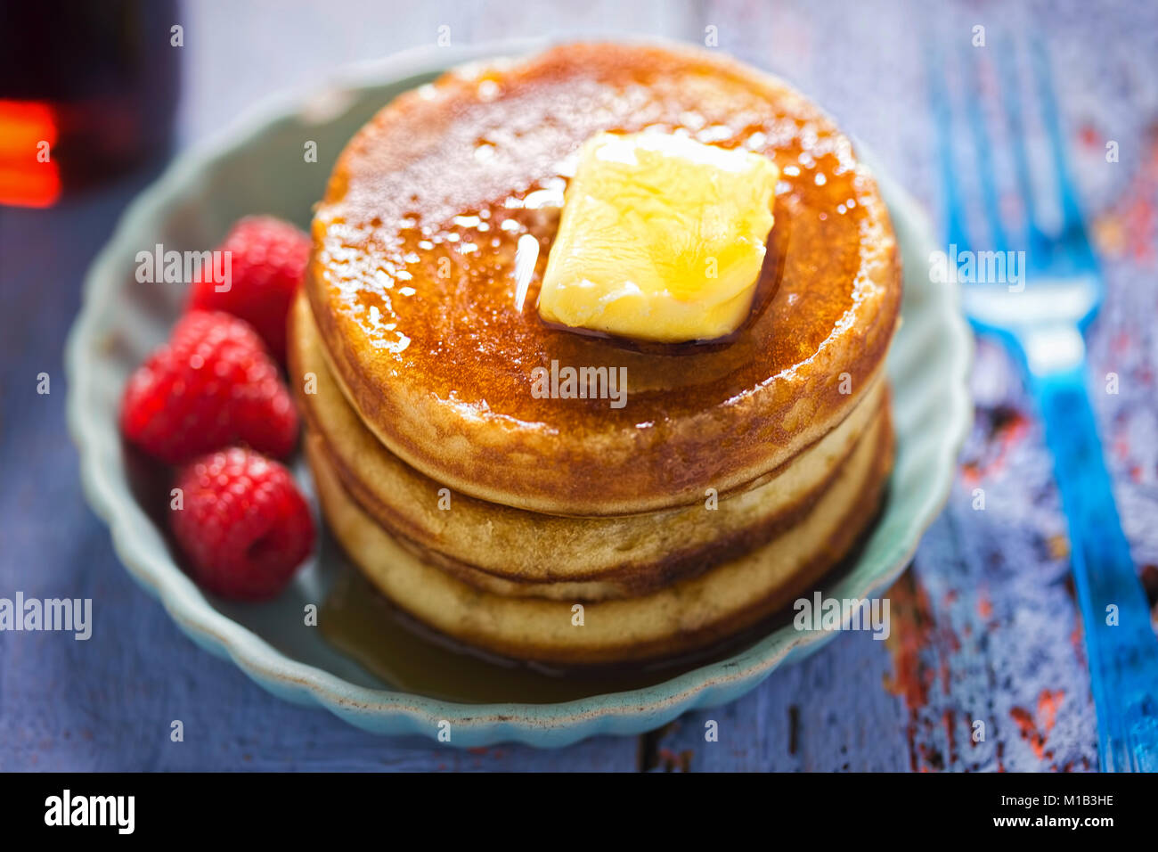 American pancakes with butter, maple syrup and raspberries Stock Photo