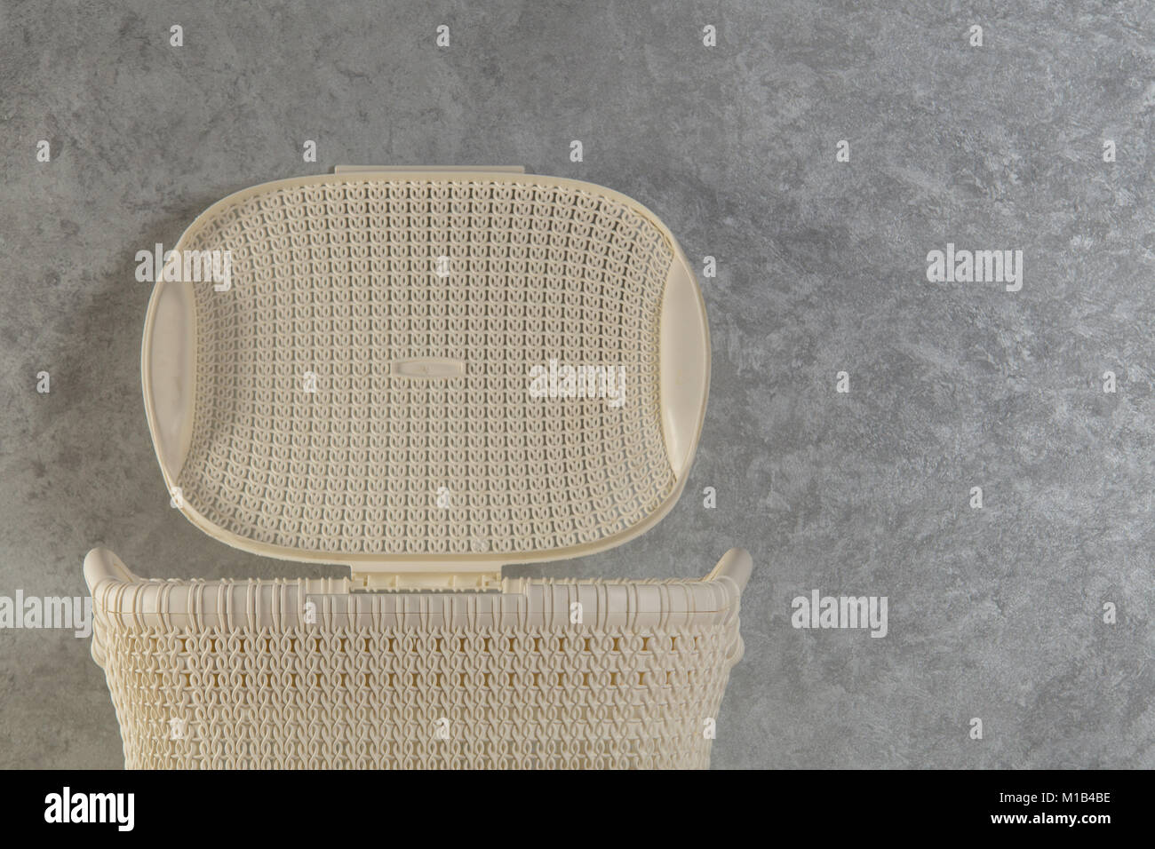 Opened white laundry basket on gray wall background close-up Stock Photo