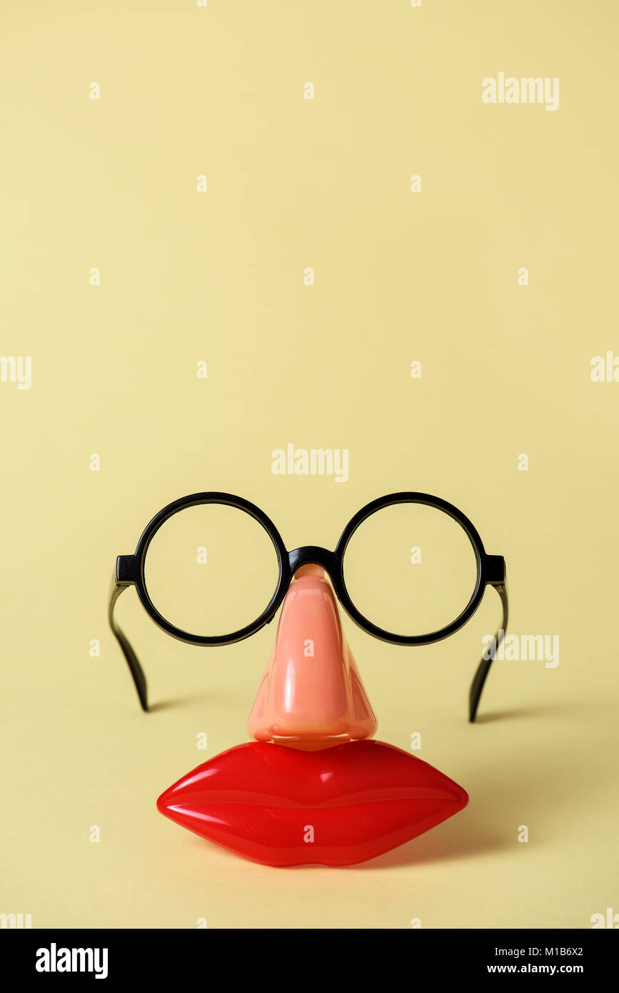 closeup of a pair of fake black glasses, a nose and a mouth forming the