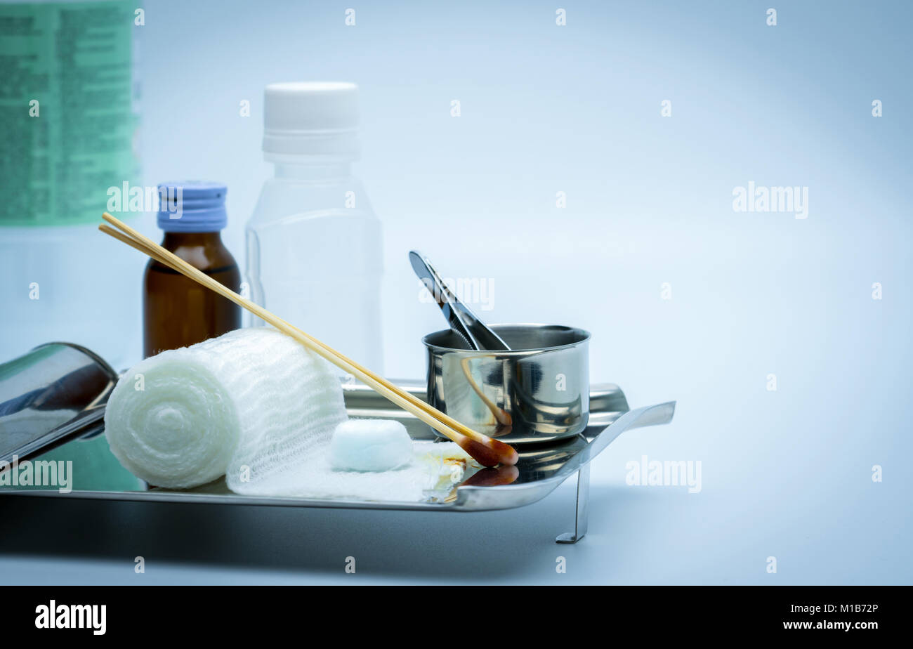 Wound care dressing set on stainless steel plate. Cotton ball with alcohol, cotton stick with povidone-iodine, forceps and conform bandage. Stock Photo