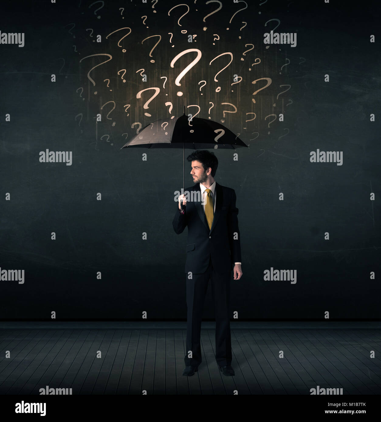 Businessman with umbrella and a lot of drawn question marks concept on