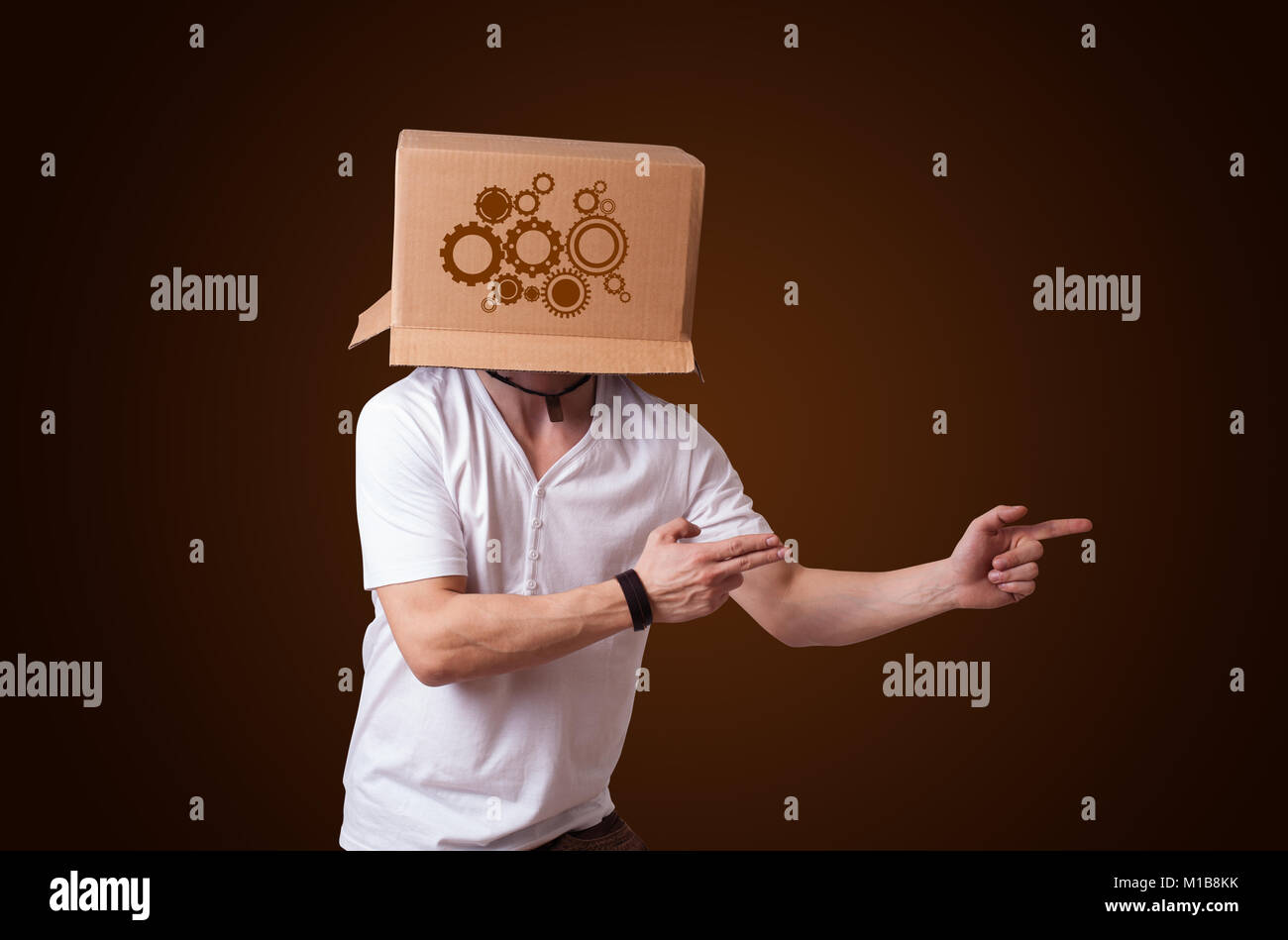 Young man standing and gesturing with a cardboard box on his head with ...