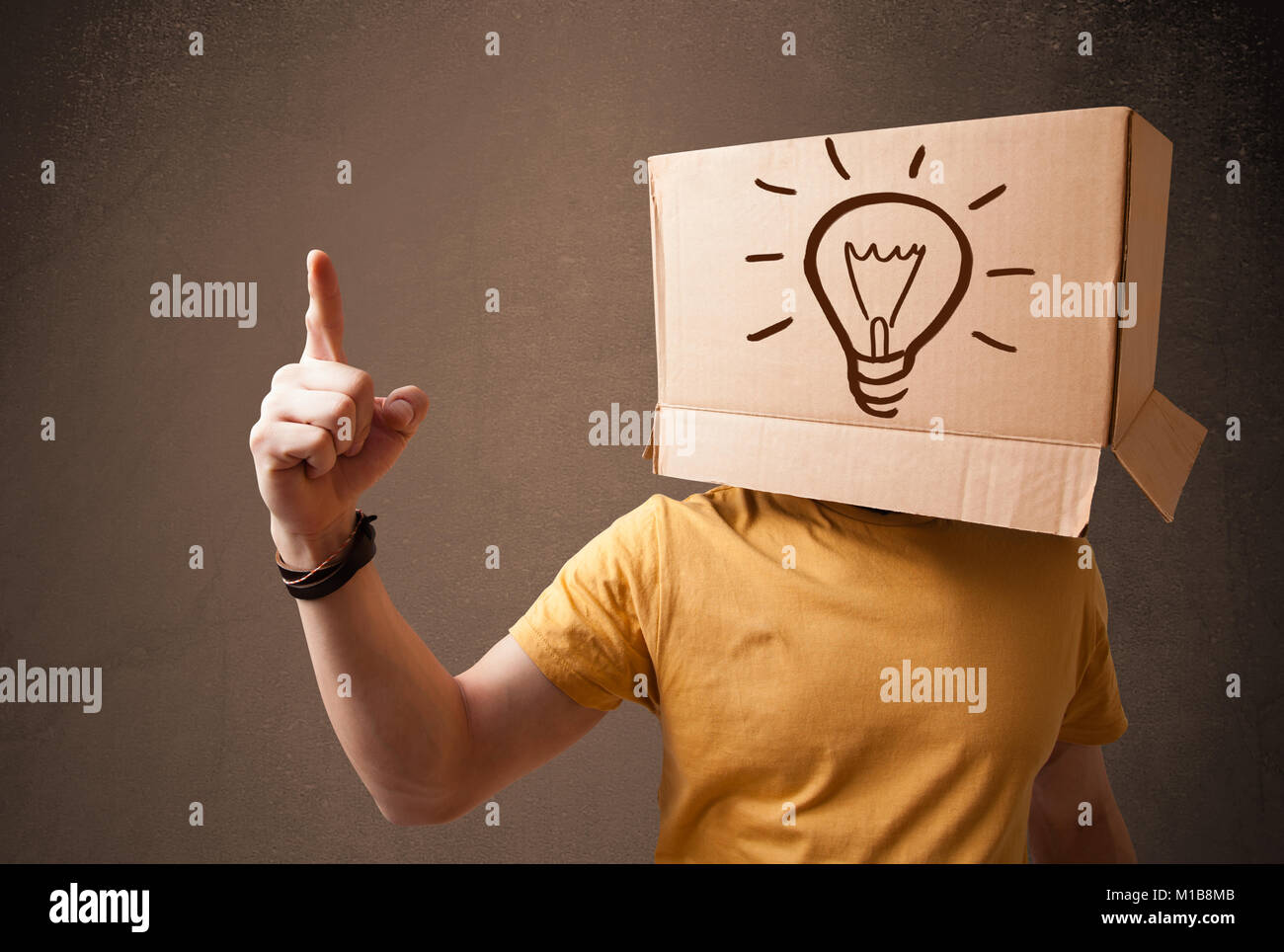 Young man standing and gesturing with a cardboard box on his head with ...