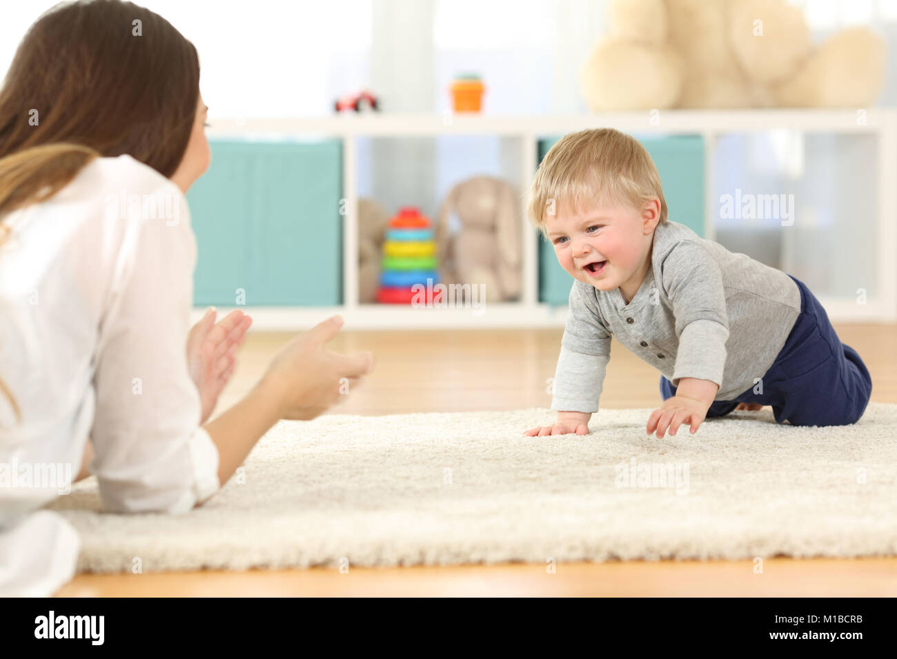 Happy baby crawling towards his mother on a carpet at home Stock Photo