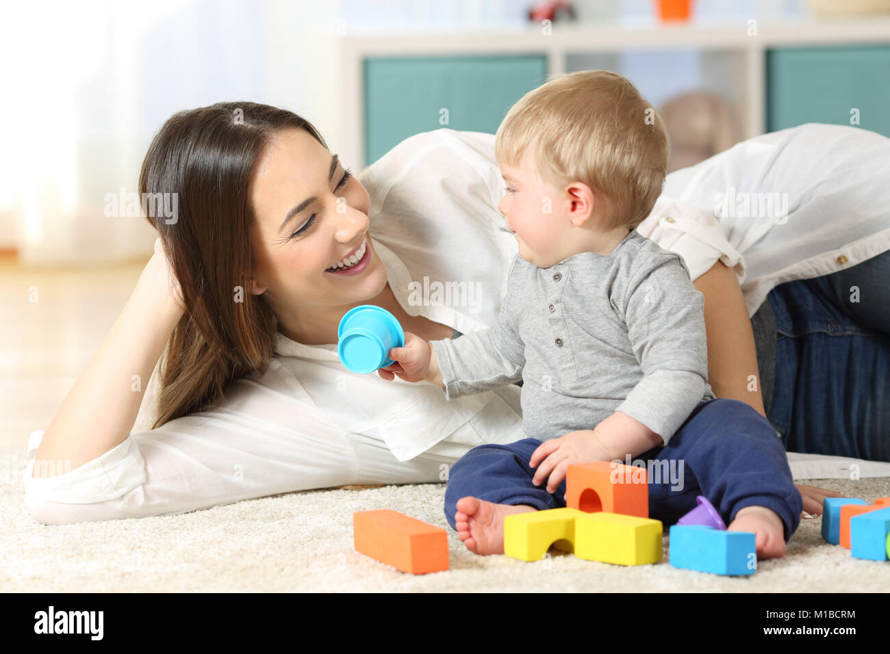 Joyful mother and baby playing with toys on a carpet at home Stock Photo