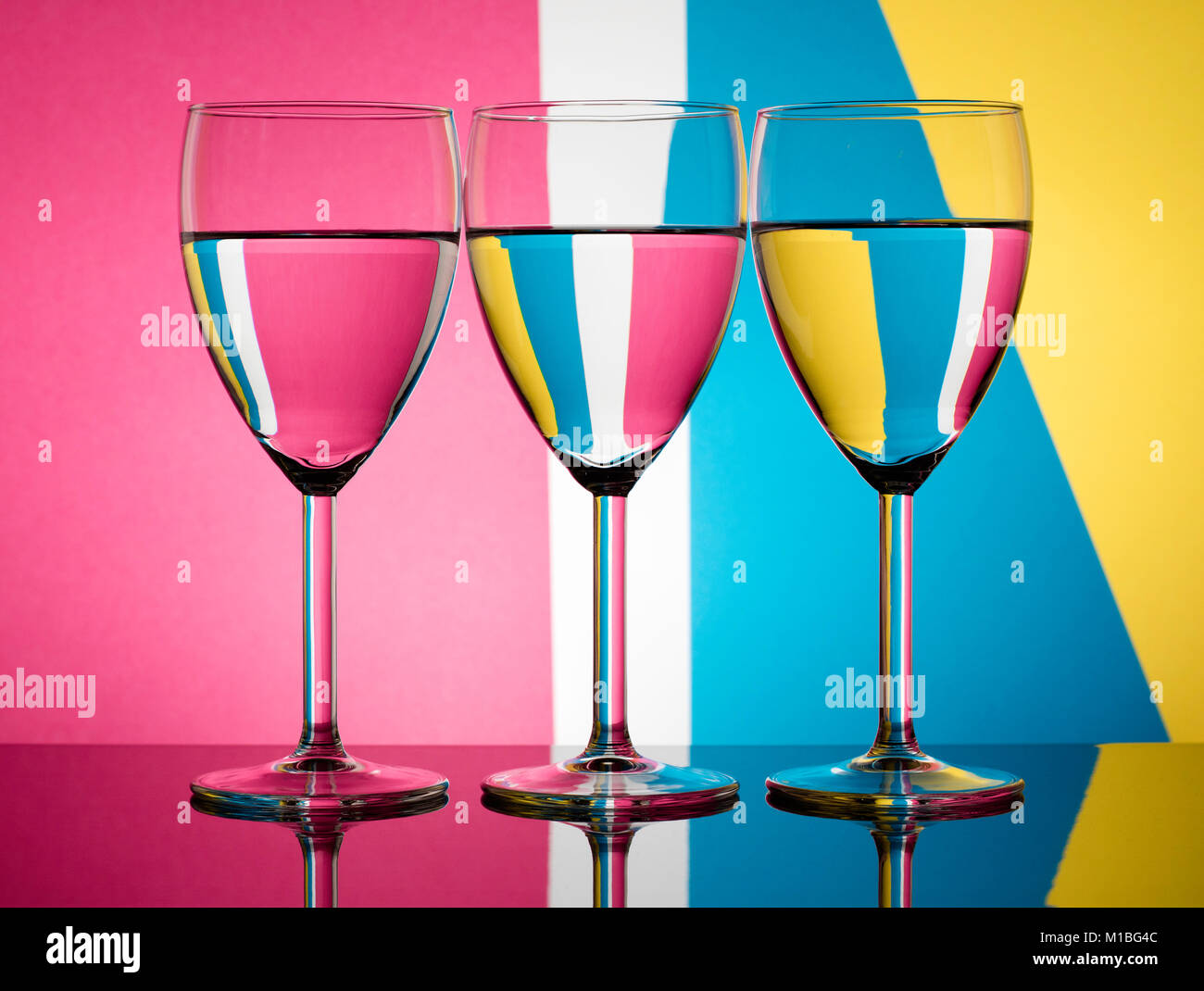 Three back lit wine glasses refracting a pastel multicolour background