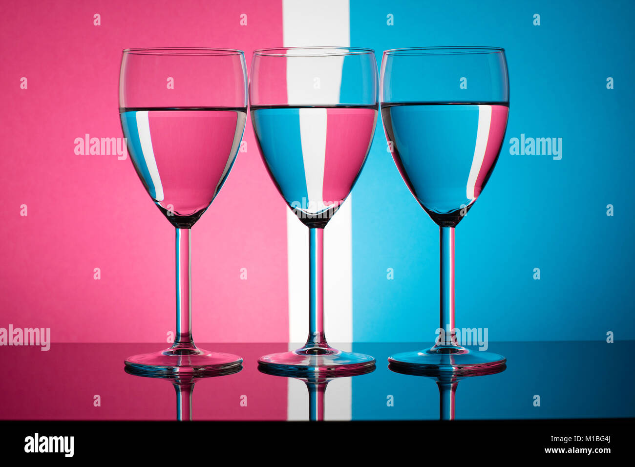 Three wine glasses refracting a pastel coloured background Stock Photo