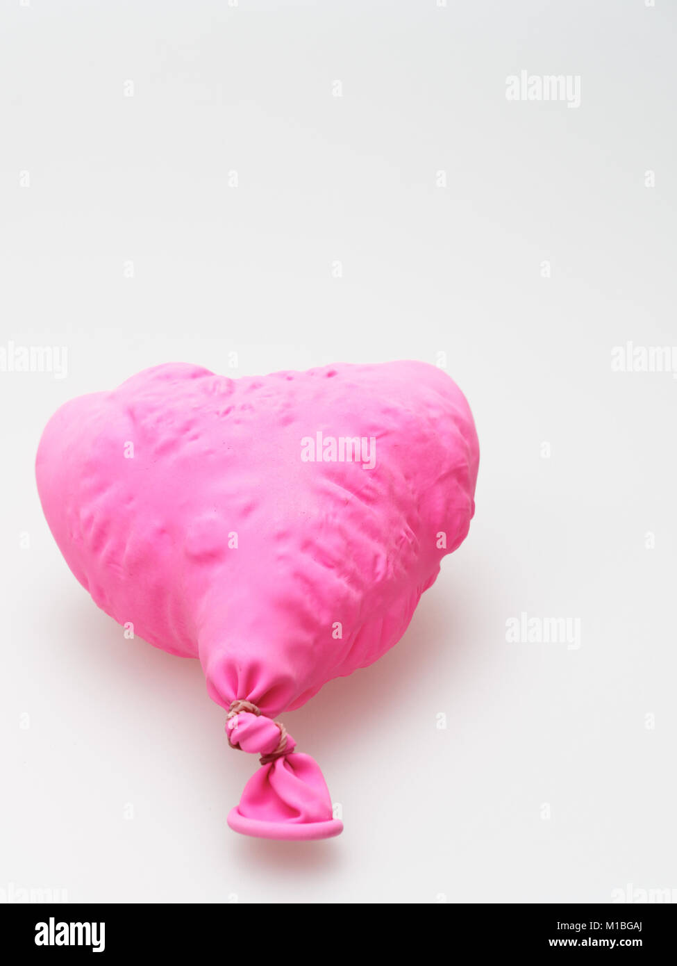 Deflate heart shape balloon in pink color isolated on white background Stock Photo