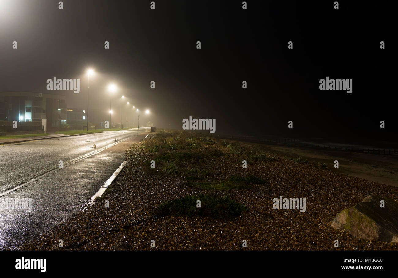 Deserted beach and seafront road lit up at night in England, UK. Stock Photo