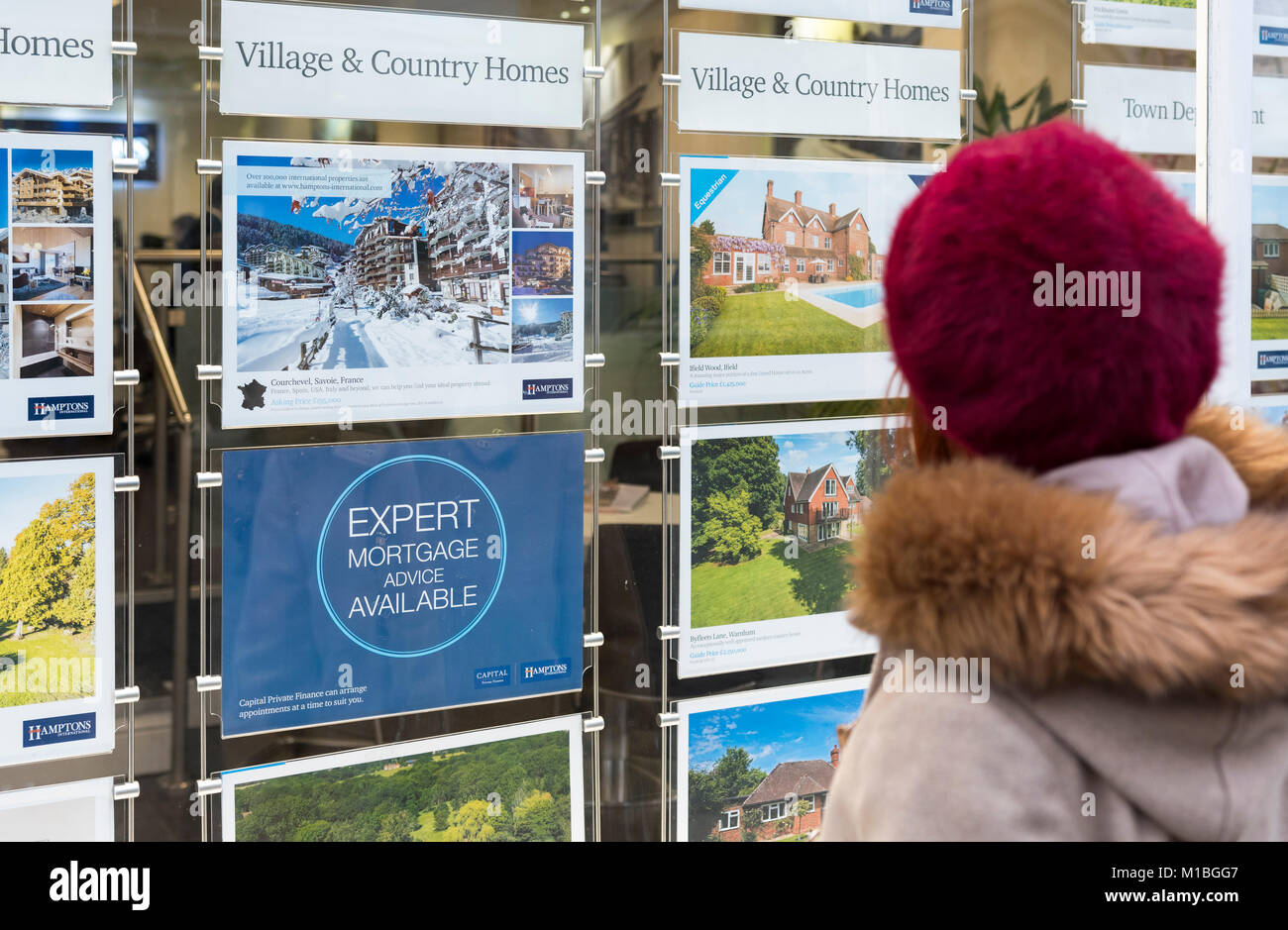 Woman looking in Estate Agents window, buying a property, in England, UK. Stock Photo