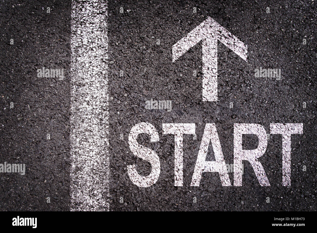 Word Start and an arrow written on an asphalt road background Stock Photo