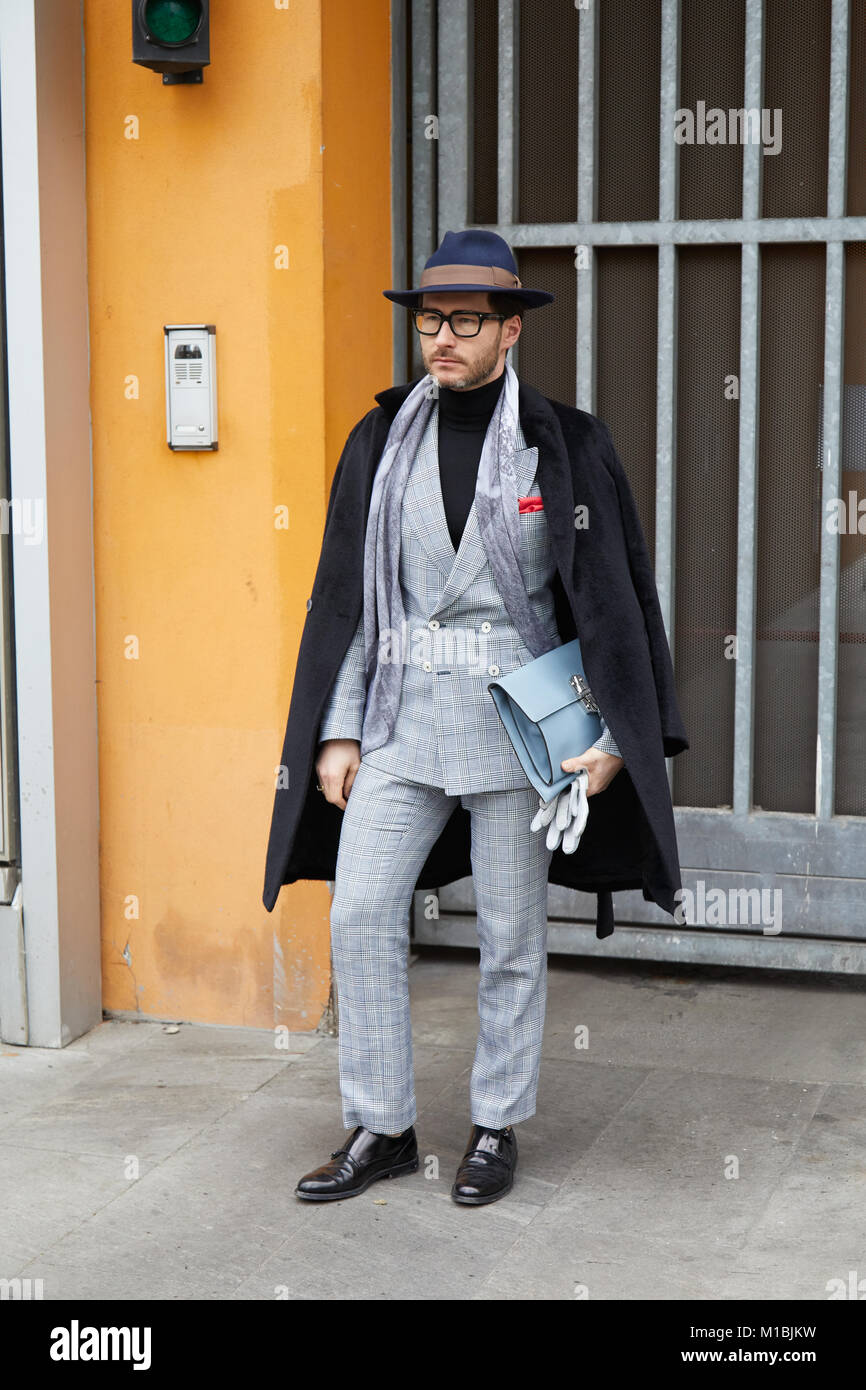MILAN - JANUARY 15: Man with gray suit and black coat before Giorgio Armani fashion show, Milan Fashion Week street style on January 15, 2018 in Milan Stock Photo