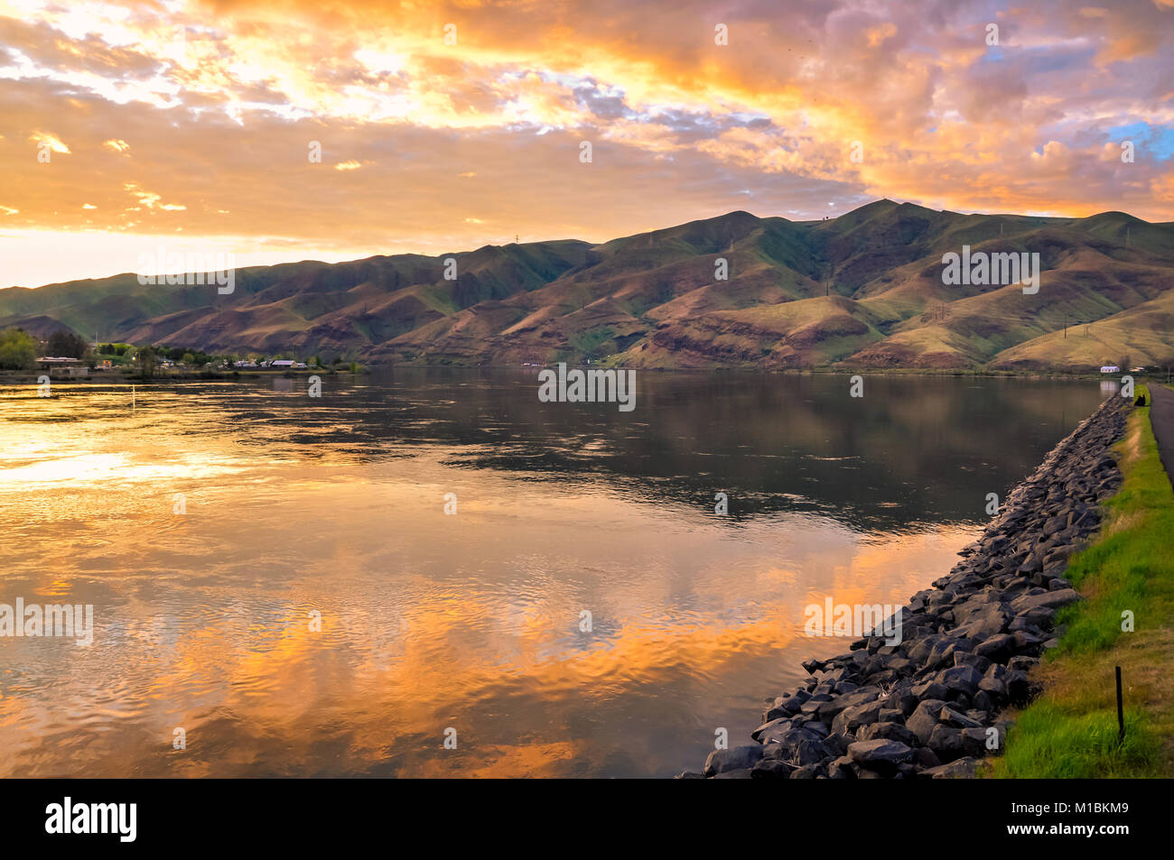 Lake with promenade, sunset sky reflection and foothills Stock Photo