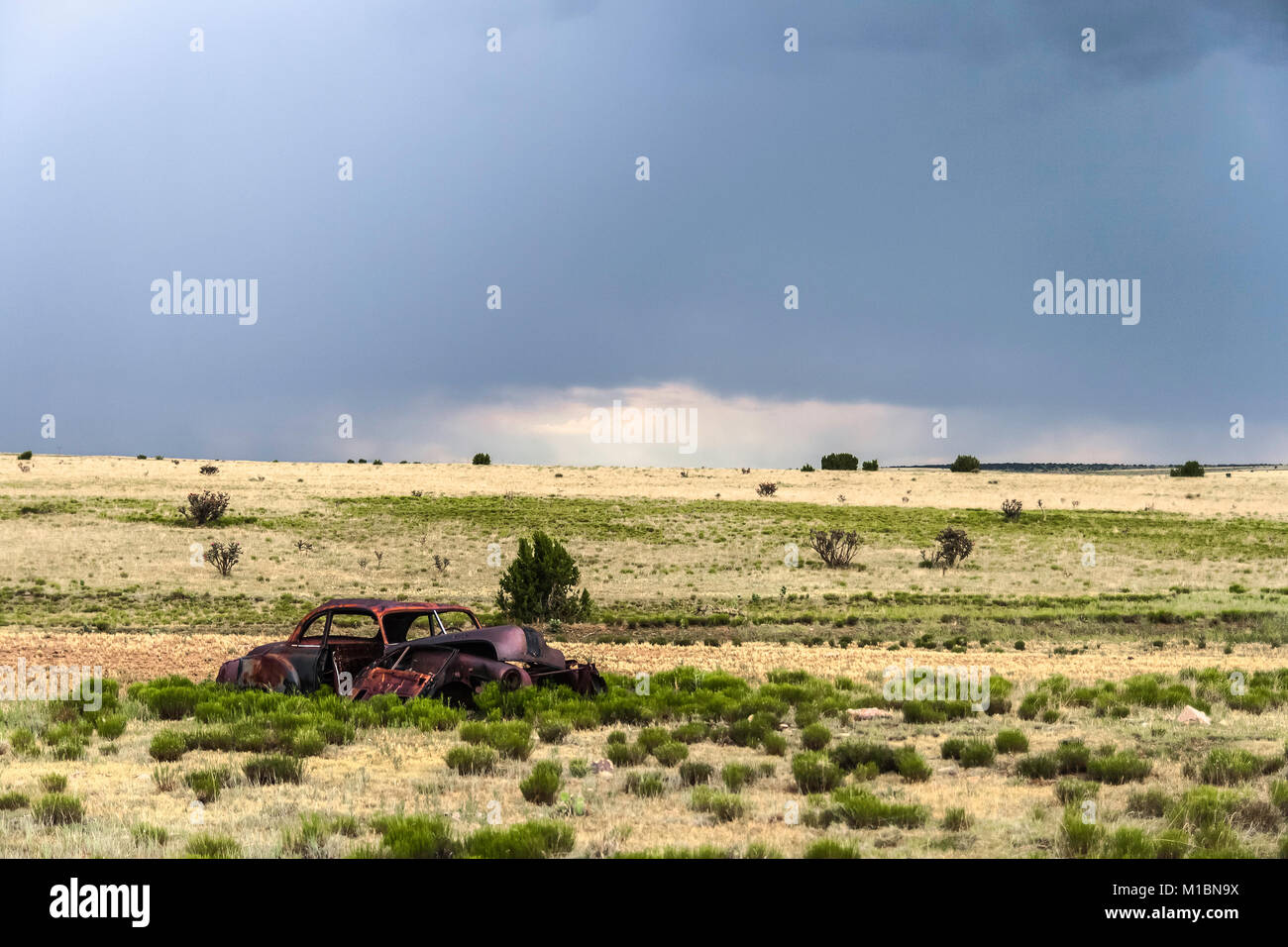 Old rusty wreckage of a car in a field alongside the road 66, New Mexico. Stock Photo