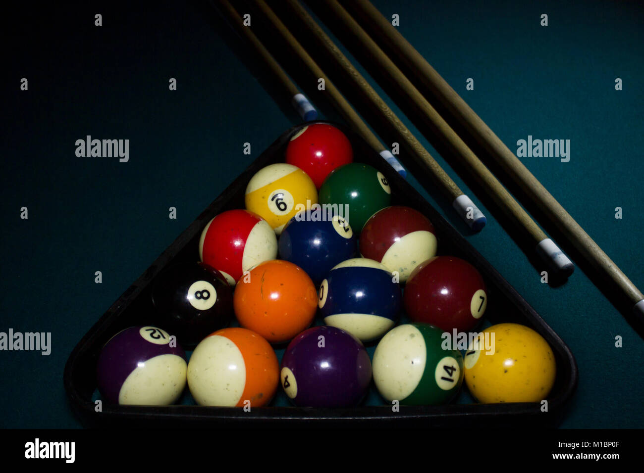 billiard balls inside the triangle with four cue sticks on green