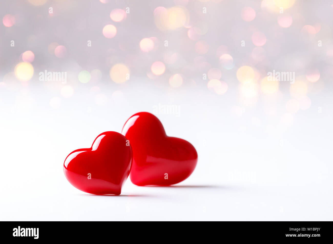 Two Red Hearts Over White Background With Bokeh Lights