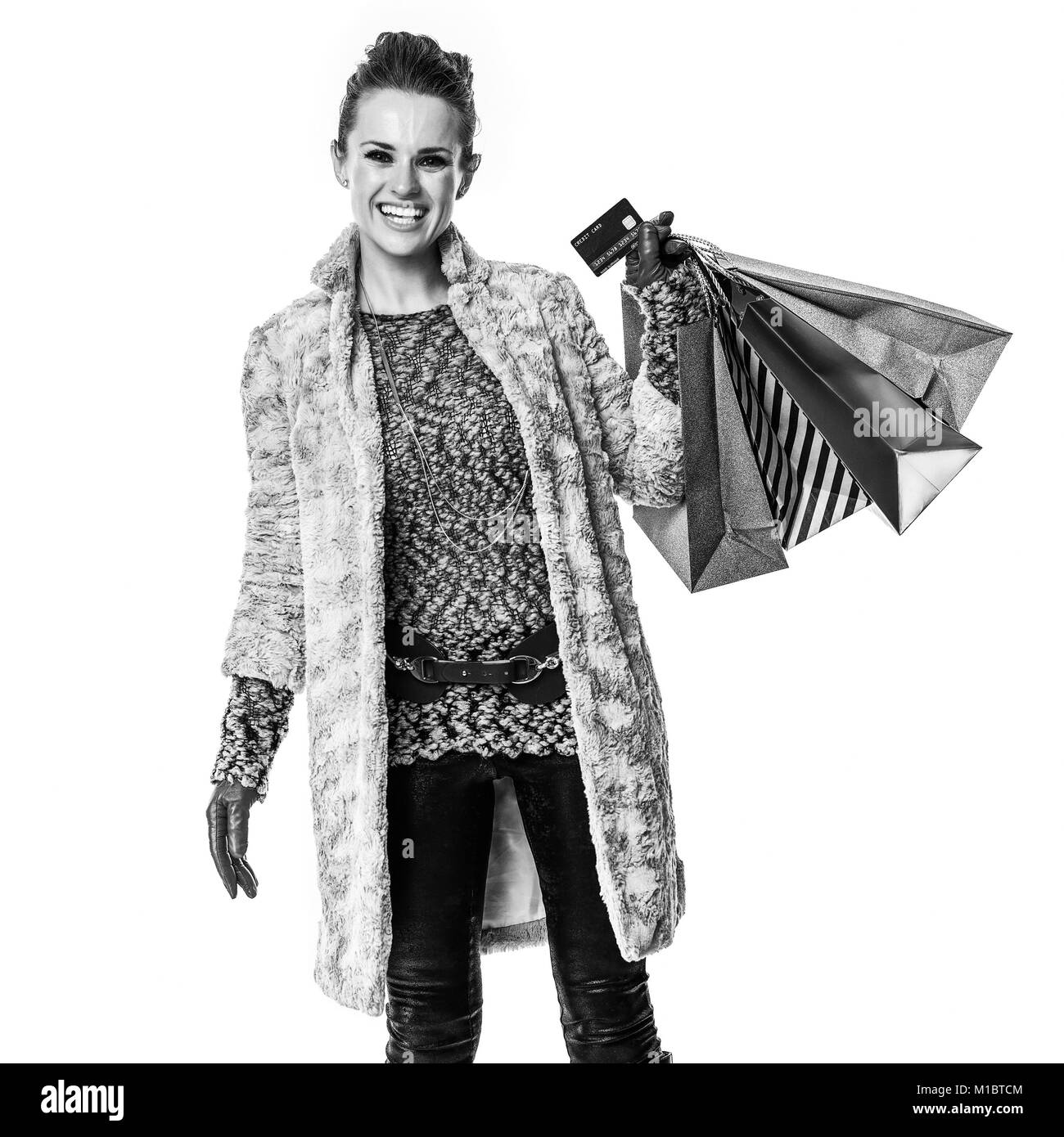 Winter things. Full length portrait of smiling trendy fashion-monger in winter coat isolated on white background with shopping bags showing credit car Stock Photo