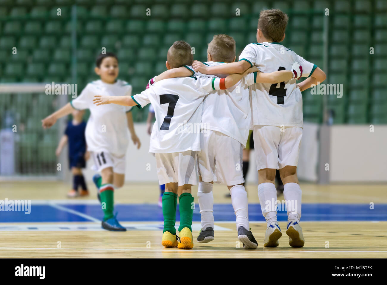 Indoor football soccer match for children. Happy kids together after winning futsal game. Chldren celebrate sport victory. Youth sport triumph Stock Photo