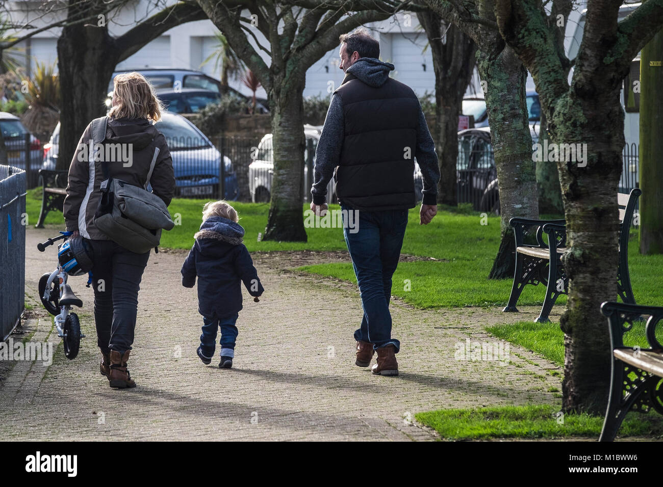 Parents and a toddler walking in a park. Stock Photo