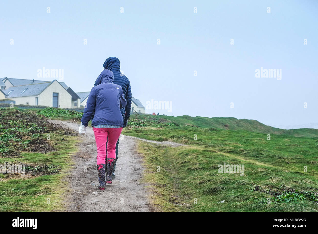 UK Winter weather - People couple walkers walking on the South West Coast Path during cold wintry weather conditions. Stock Photo