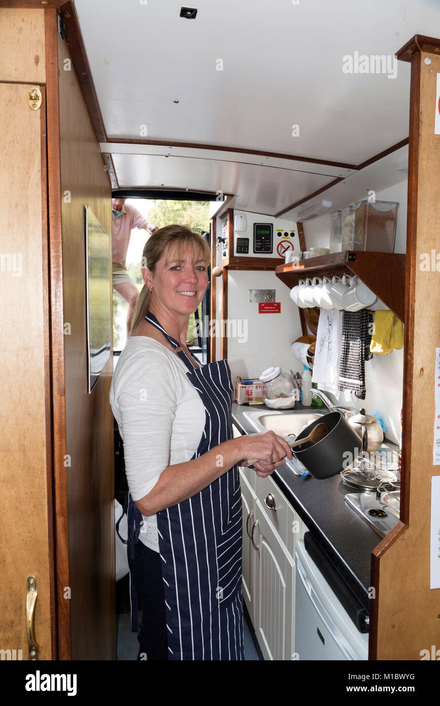 Holidaymaker working in the galley of a narrowboat during a canal cruising holiday Stock Photo