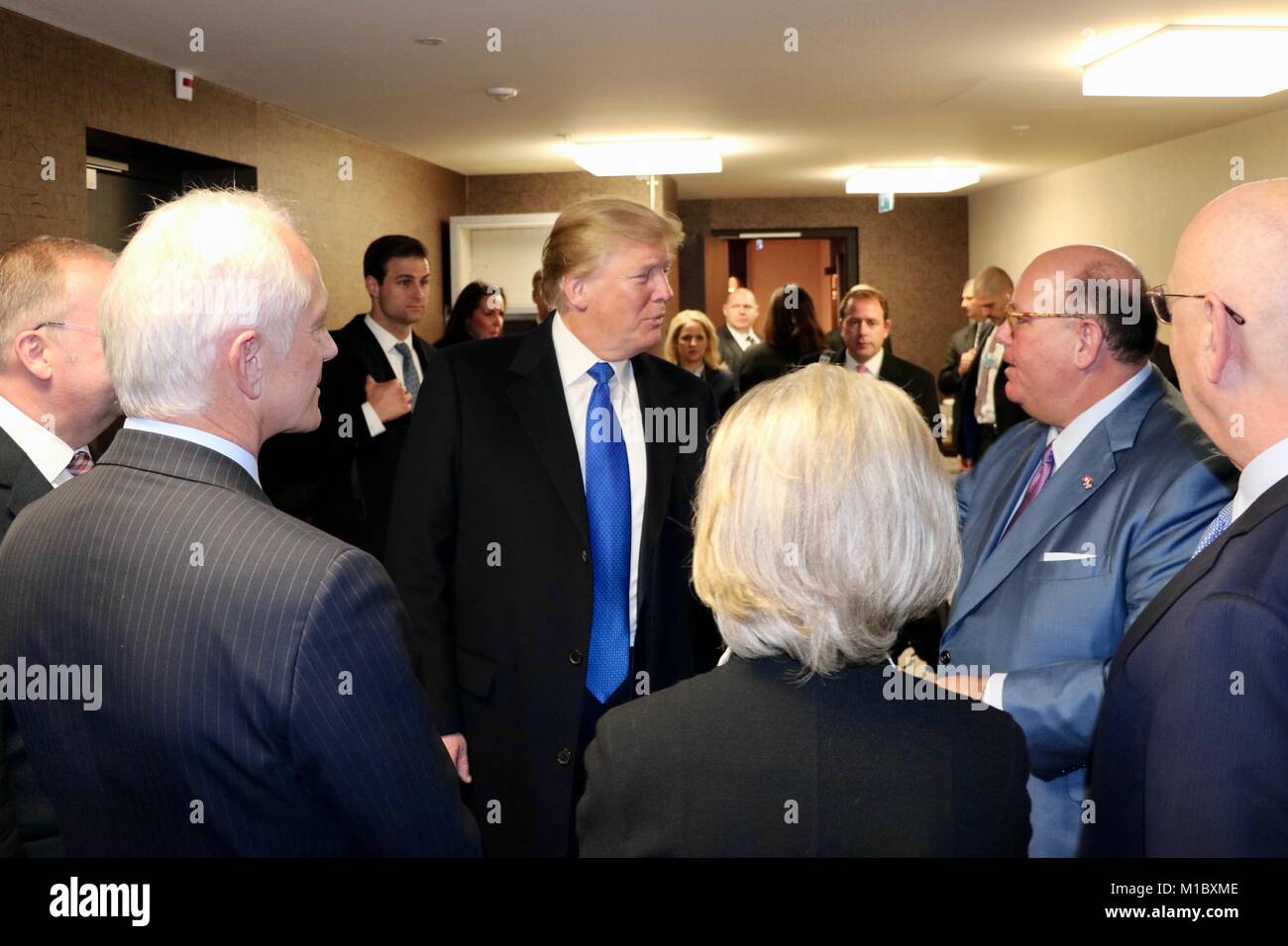 U.S President Donald Trump chats with U.S. Ambassador to Switzerland Ed McMullen, right, along with WEF Chairman Klaus Schwab, Hilde Schwab, Davos Mayor Tarzisius Caviezel, WEF Managing Director Alois Zwinggi look on as he arrives to attend the World Economic Forum January 25, 2018 in Davos, Switzerland. Stock Photo