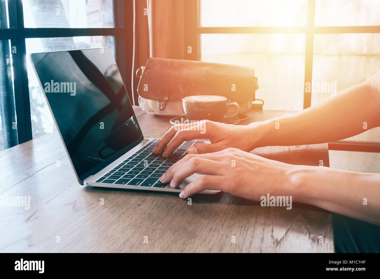Man hands typing on laptop on table in coffee shop with len flare and warm filter with free wifi ,concept for freelance can working any time anywhere. Stock Photo