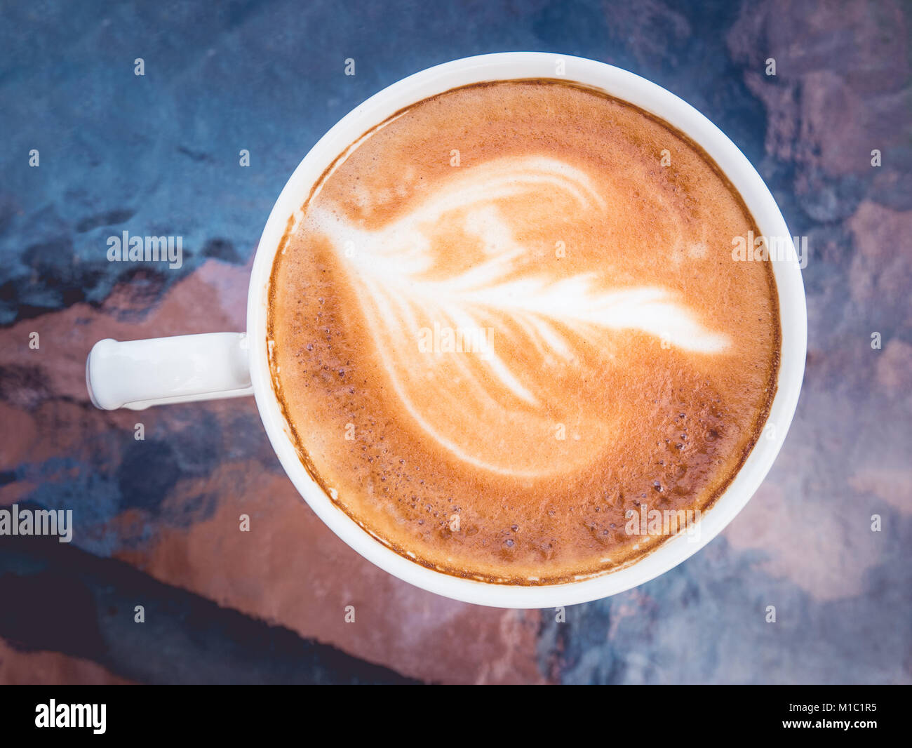 Hot coffee with latte art on table in coffee shop for background or cafe menu design. Stock Photo